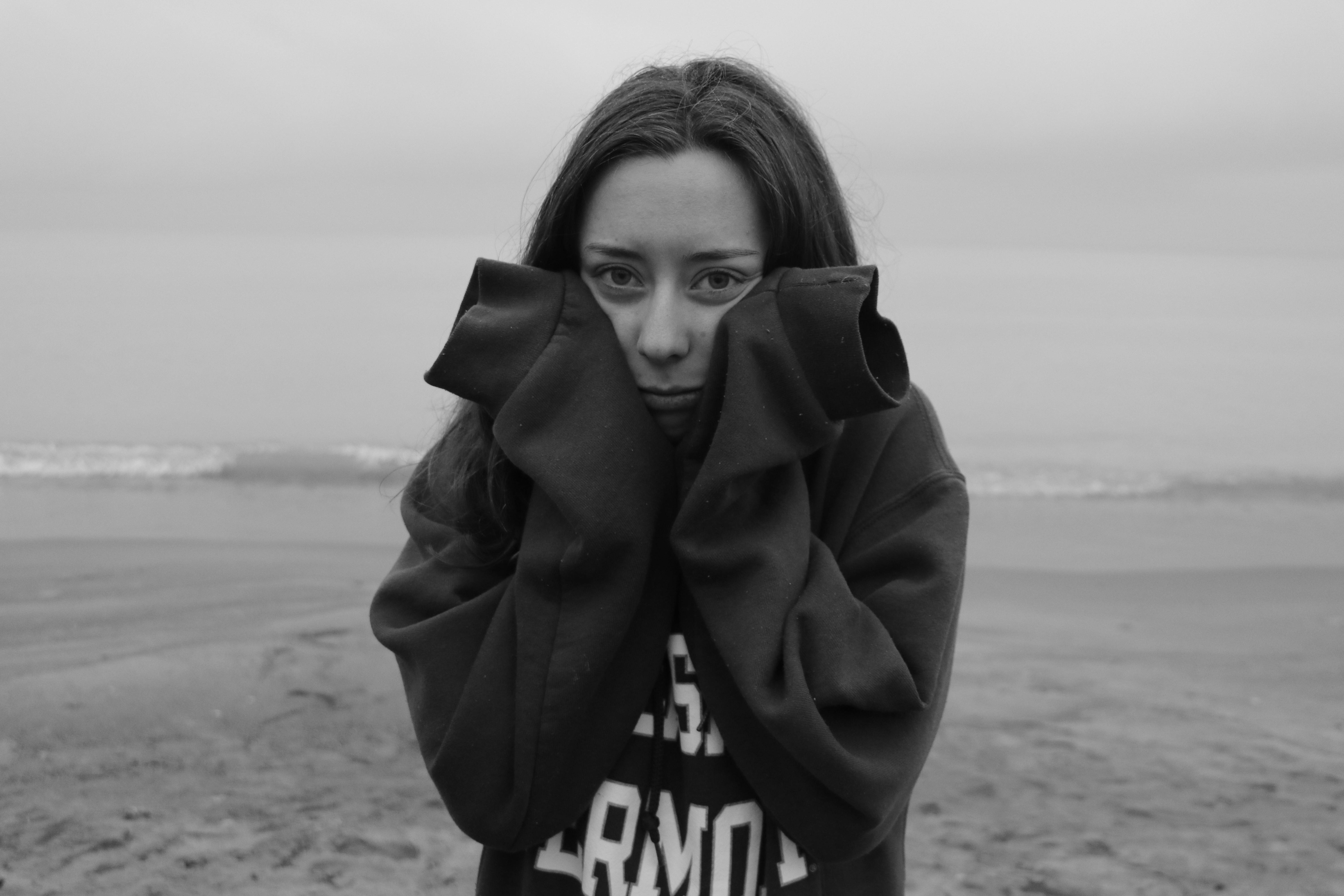 woman holds face in hands at the beach