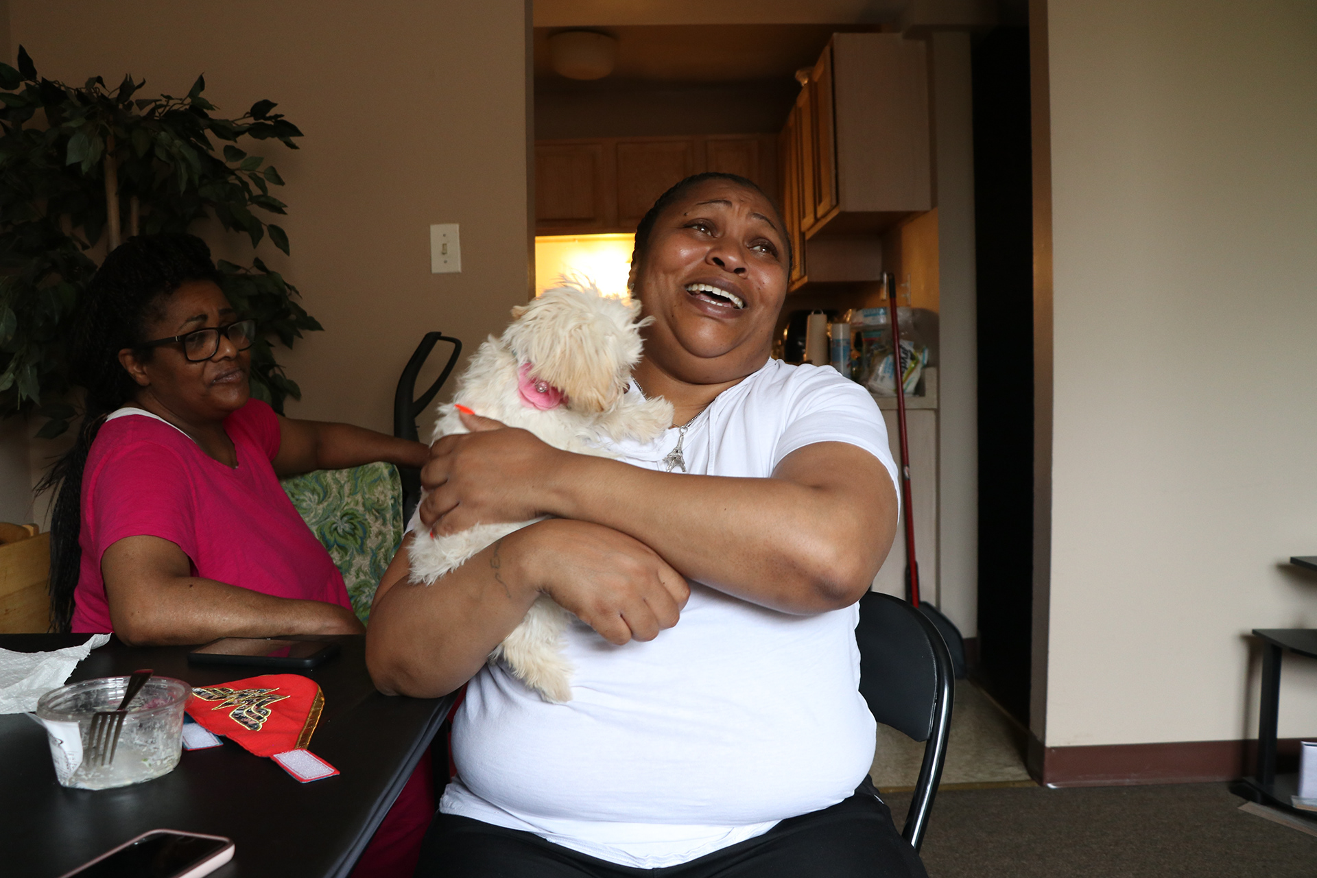 Woman laughs while holding small white dog